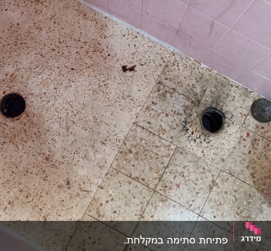 רצפת חדר אמבטיה עם חור ניקוז פתוח ופקק שחור
